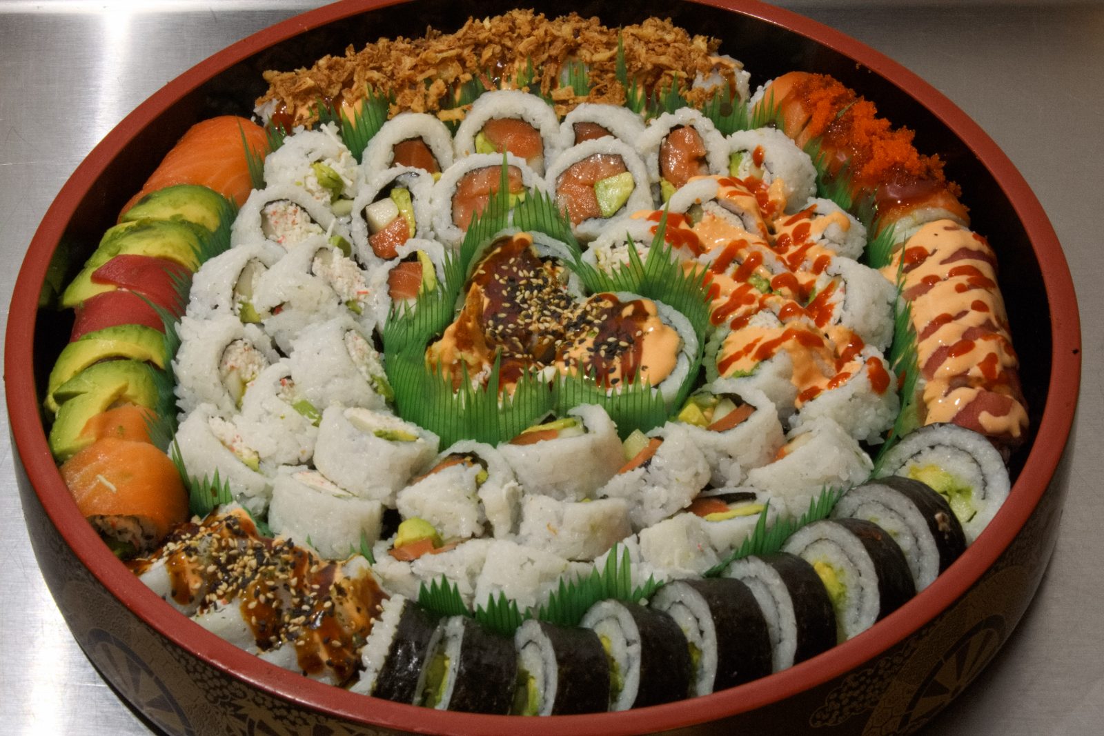 Mixed sushi tray with house rolls at the center